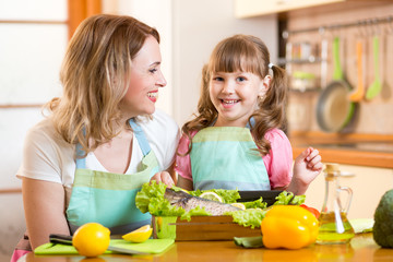 happy mom and kid cooking healthy food in kitchen