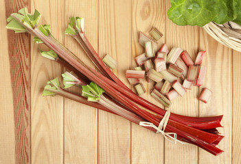 Bundle of fresh rhubarb stalks and chops on table, high angle