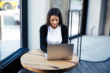 Attractive businesswoman using laptop in cafe