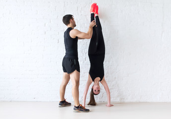 woman sportsman doing a handstand against concrete wall male