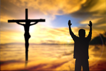 Fototapeta premium Silhouette of man with raised hands over blur cross concept for