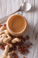 peanut butter in a glass jar and nuts vertical top view
