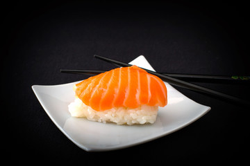 Salmon nigiri sushi and chopstick on black