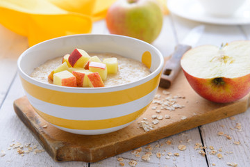 Oatmeal porridge with slice of apples in striped bowl
