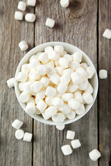 Marshmallows in bowl on grey wooden background