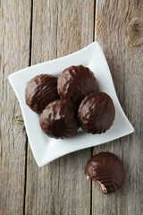 Zephyr in chocolate on plate on grey wooden background