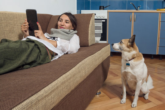 Young Woman Reading From Her Tablet And Her Dog