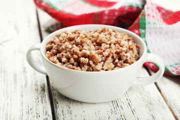 Buckwheat in bowl on white wooden background