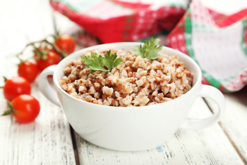 Buckwheat in bowl on white wooden background