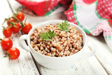 Buckwheat in bowl on white wooden background