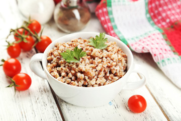 Buckwheat in bowl on white wooden background
