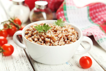 Buckwheat in bowl on white wooden background