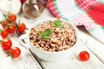 Buckwheat in bowl on white wooden background