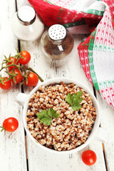 Buckwheat in bowl on white wooden background