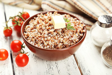 Buckwheat in bowl on white wooden background