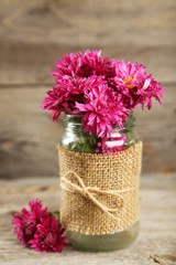 Beautiful purple chrysanthemums in glass on wooden background