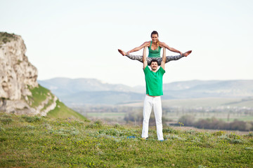 Acroyoga. Woman and man doing yoga on mountain