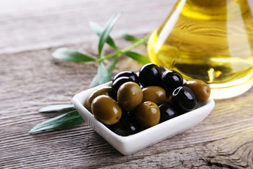 Green and black olives in bowl on grey wooden background