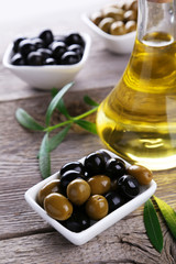 Green and black olives in bowl on grey wooden background