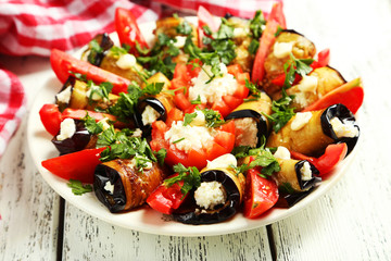 Tasty eggplant rolls on white wooden background