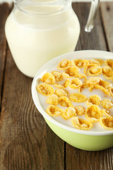 Bowl of cornflakes with milk on brown wooden background