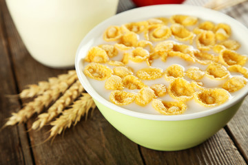 Bowl of cornflakes with milk on brown wooden background