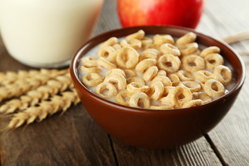 Bowl of cornflakes with milk on brown wooden background