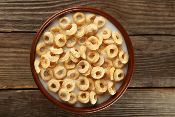 Bowl of cornflakes with milk on brown wooden background