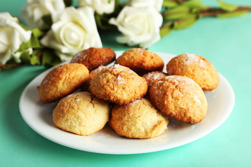 Coconut cookies on plate on green background
