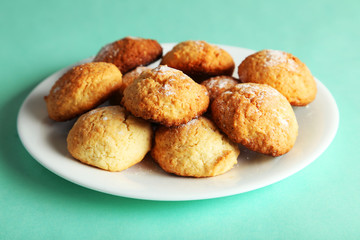 Coconut cookies on plate on green background