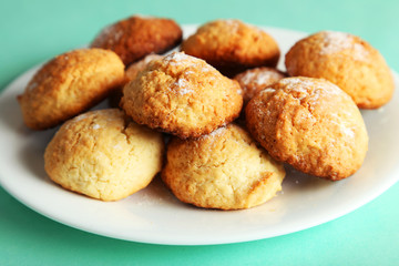 Coconut cookies on plate on green background