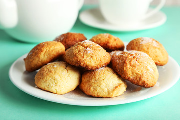 Coconut cookies on plate on green background