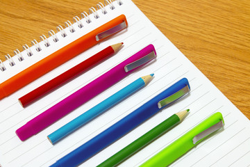 Fototapeta premium colored pens and pencils on a notepad on the table