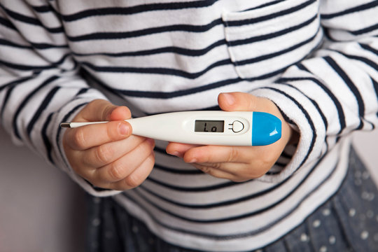 Small child's hands holding thermometer