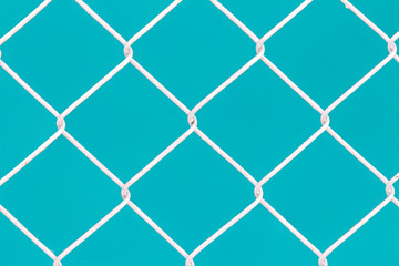Fototapeta premium White wire fence on green background