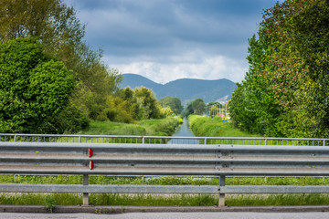 Fototapeta premium Panorama monti e canale, corso d' acqua, guard rail