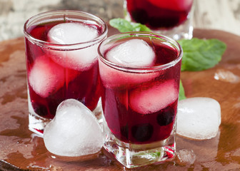 Red berry juice with ice in the shape of hearts, selective focus