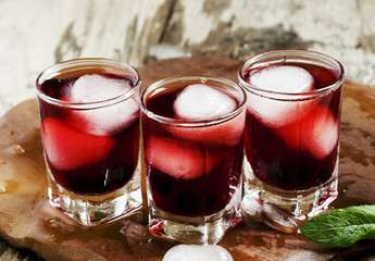 Red berry juice with ice in the shape of hearts, selective focus