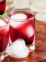 Red berry juice with ice in the shape of hearts, selective focus