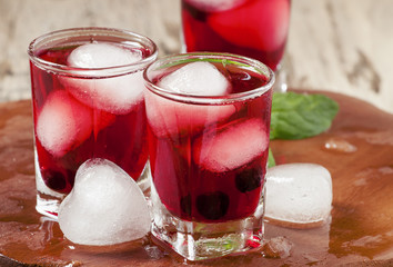 Red berry juice with ice in the shape of hearts, selective focus