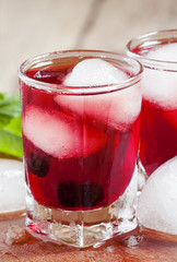 Red berry juice with ice in the shape of hearts, selective focus