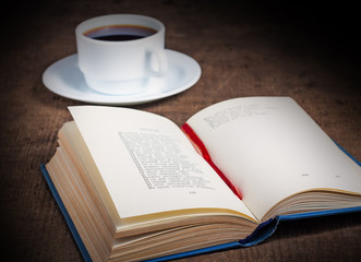 Open book with a cup of coffee on wooden table