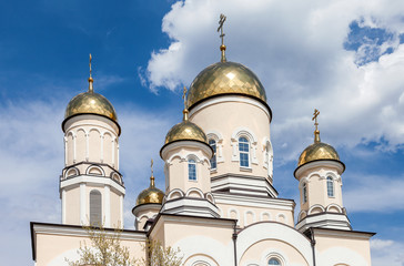 Fototapeta na wymiar Golden domes of Russian orthodox church with cross against blue