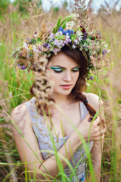 Young beautiful woman with flower wreath at the meadow