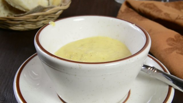 Ladling cream of broccoli soup into a cup
