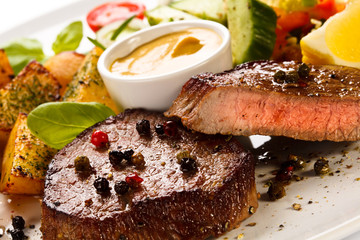 Steaks, baked potatoes and vegetable salad 