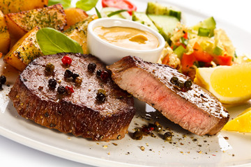 Steaks, baked potatoes and vegetable salad 
