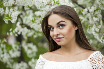 Naklejka premium Happy young woman in white dress against the background spring f