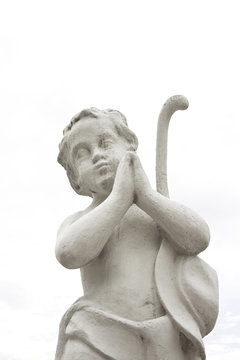 Statue of a cherub praying on white background with copy space.