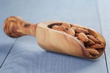 roasted almonds in measuring scoop on blue wooden table